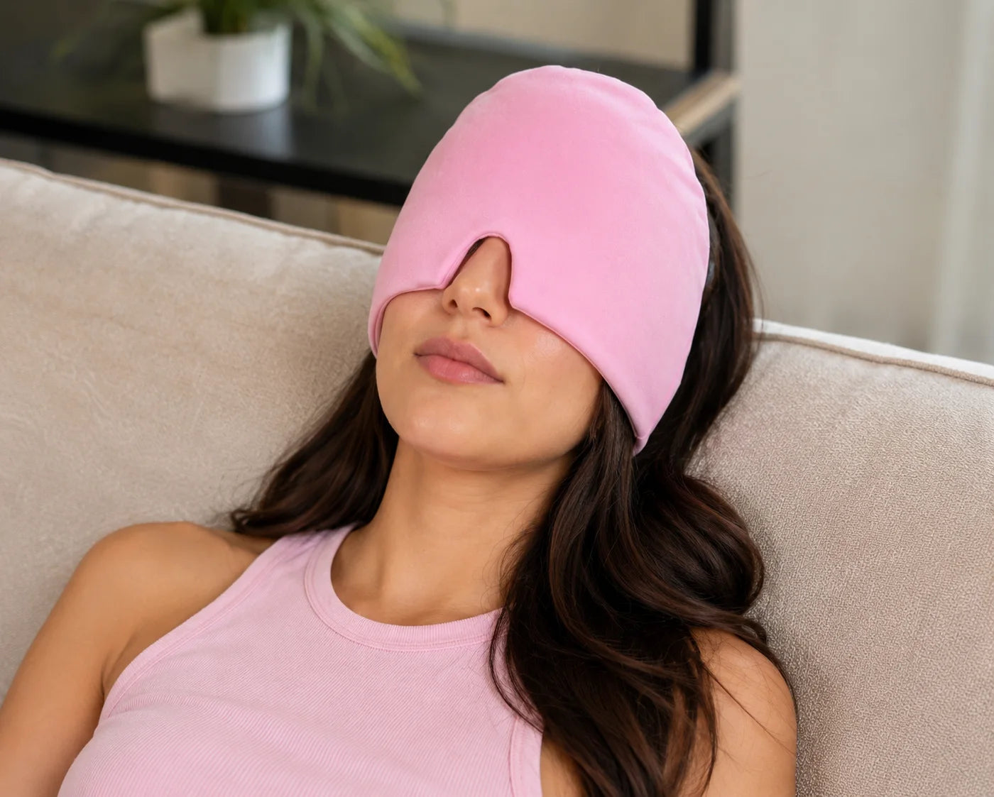 A woman reclining with a pink NuraCool cap over her eyes