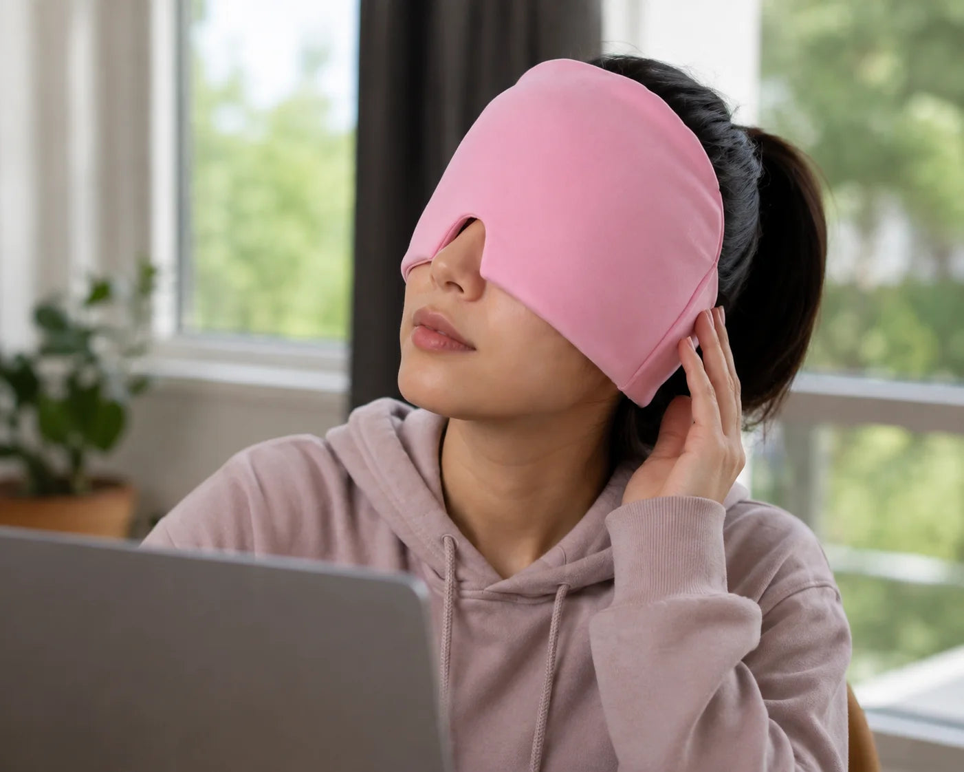A woman wearing a pink NuraCool cap near a window